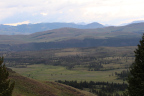 Photo of a landscape with gently undulating hills in the foreground and craggy mountains in the background