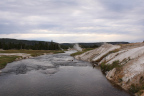 Photo of a landscape with a river and its banks in the foreground and steam rising from hot springs in the background